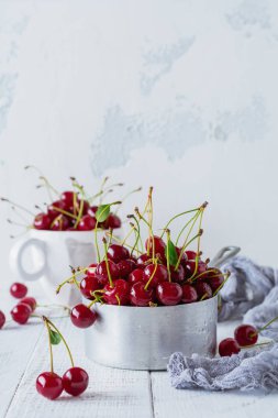 Hafif ahşap eski arka plan üzerinde rustik alüminyum tencerede taze kiraz.
