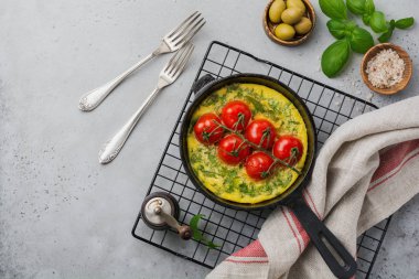 Frittata roka, patates ve domates eski taş tablo arka demir tavada. Üstten görünüm.