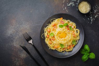 Makarna spagetti carbonara pastırma, kaşar peyniri, yumurta sarısı ve fesleğen ile siyah arka plan üzerine bırakır. Geleneksel İtalyan yemeği. Üstten görünüm.