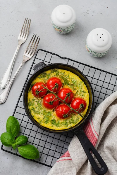 Frittata roka, patates ve domates eski taş tablo arka demir tavada. Üstten görünüm.