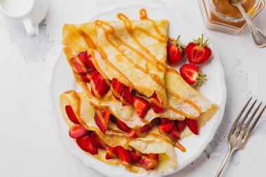 Taze çilek ve gri beton zemin üzerine ballı krep. Üstten görünüm.