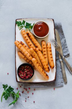 Izgara Barbekü sos ve ketçap ve karanlık beton zemin üzerine seramik plaka üzerinde sarımsak sosis. Üstten görünüm.