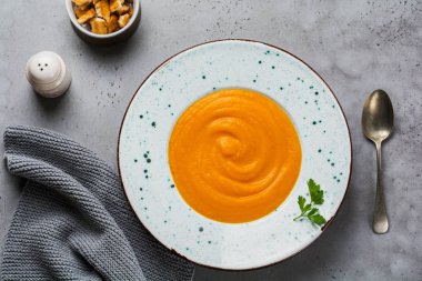 Kabak çorba krema, ekmek ve sedir parçalar ile gri tablo arka planı gri Seramik plaka hayalarına. Geleneksel sonbahar gıda. Üstten görünüm kopya alanı.