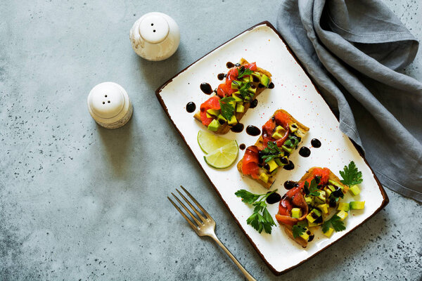 Сэндвичи с авокадо и лососем с бальзамическим соусом и кинзой на старой оливковой доске. Вид сверху
.