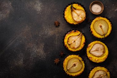 Armut ve koyu kahverengi beton eski tablo arka plan üzerinde muhallebi mini turta. Üstten görünüm.