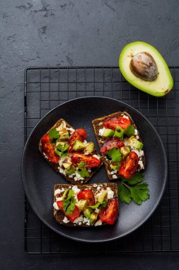 Avokado, domates ve beyaz peynirli sandviç Balsamik Sos ve Salantro koyu siyah arka plan üzerine eski zeytin gemide. Üstten görünüm.