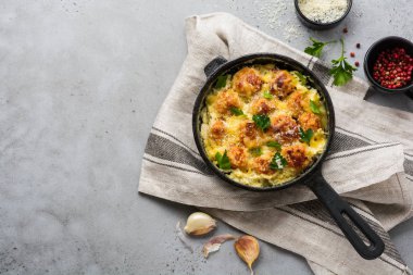 Peynirli ve krem soslu köfteler gri renkli arka planda dökme demir tavada. Üst görünüm.