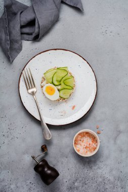 Gri beton zemin üzerine salatalık, yumurta ve lor peynirli sandviç. Üstten görünüm.