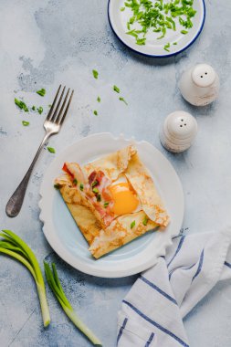 Sahanda yumurta, peynir, pastırma ve yeşil soğan bir ışık gri beton zemin üzerine kahvaltıda krep.