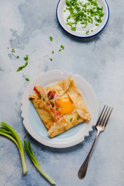 Sahanda yumurta, peynir, pastırma ve yeşil soğan bir ışık gri beton zemin üzerine kahvaltıda krep.