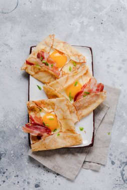 Sahanda yumurta, peynir, pastırma ve yeşil soğan bir ışık gri beton zemin üzerine kahvaltıda krep.