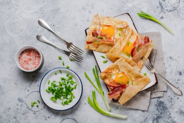 Sahanda yumurta, peynir, pastırma ve yeşil soğan bir ışık gri beton zemin üzerine kahvaltıda krep.