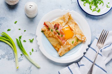 Sahanda yumurta, peynir, pastırma ve yeşil soğan bir ışık gri beton zemin üzerine kahvaltıda krep.