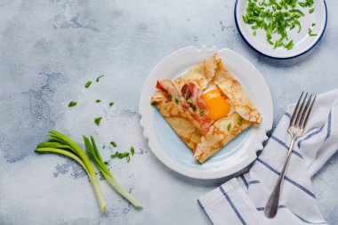 Sahanda yumurta, peynir, pastırma ve yeşil soğan bir ışık gri beton zemin üzerine kahvaltıda krep.