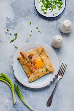 Sahanda yumurta, peynir, pastırma ve yeşil soğan bir ışık gri beton zemin üzerine kahvaltıda krep.