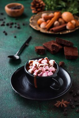 Anason ve fındık eski koyu yeşil beton zemin üzerine siyah seramik Kupası ile sıcak çikolata. Seçici odak.