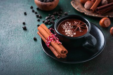 Anason ve fındık eski koyu yeşil beton zemin üzerine siyah seramik Kupası ile sıcak çikolata. Seçici odak.