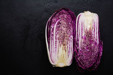 Taze çiğ mor Çince lahana siyah bir beton eski arka plan ikiye böldüm. Üstten görünüm.