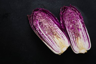 Taze çiğ mor Çince lahana siyah bir beton eski arka plan ikiye böldüm. Üstten görünüm.