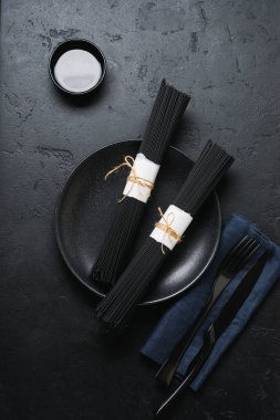 Karanlık bir beton eski arka plan üzerinde siyah spagetti. Mürekkep balığı mürekkep ile ham Kuru makarna. Üstten görünüm.