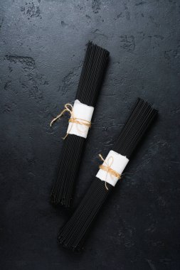 Karanlık bir beton eski arka plan üzerinde siyah spagetti. Mürekkep balığı mürekkep ile ham Kuru makarna. Üstten görünüm.