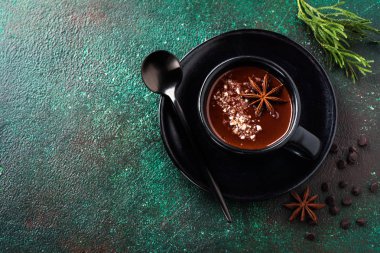 Anason ve fındık eski koyu yeşil beton zemin üzerine siyah seramik Kupası ile sıcak çikolata. Seçici odak.