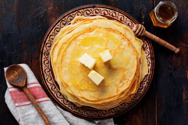 Adet tereyağı, süt ve bal eski Rustik Seramik plaka üzerinde ev yapımı ince krep yığını. Üstten Görünüm 