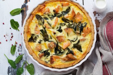 Kırmızı balık ve hafif ahşap zemin üzerine ıspanak ile ev yapımı kiş tart. Vintage tarzı. Üstten Görünüm.