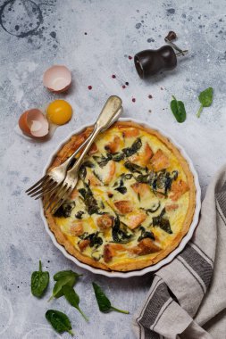 Kırmızı balık ve hafif ahşap zemin üzerine ıspanak ile ev yapımı kiş tart. Vintage tarzı. Üstten Görünüm.