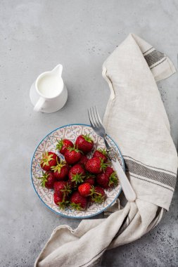 Gri eski beton zemin üzerine ışık plaka üzerinde taze çilek. Üstten görünüm.