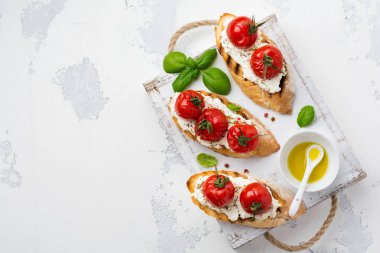 Pişmiş domates, sarımsak, zeytinyağı ve beyaz zemin üzerine Lor peynir sandviç. İtalyan mutfağı. Üstten görünüm