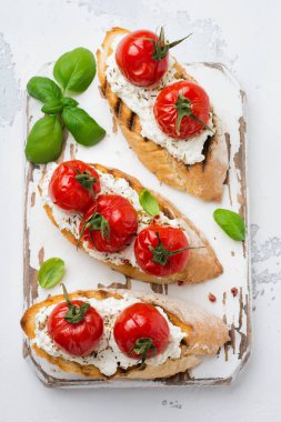 Pişmiş domates, sarımsak, zeytinyağı ve beyaz zemin üzerine Lor peynir sandviç. İtalyan mutfağı. Üstten görünüm