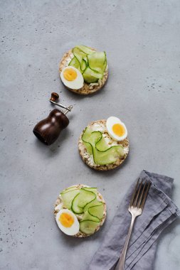 Gri eski arka plan üzerinde seramik plaka üzerinde haşlanmış yumurta ve salatalık ile Sandviç. Üstte görüntü.