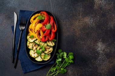 Izgara sebze parçaları kabak, kırmızı ve sarı biber tabakta kişniş buketi, mangal kömürünün üzerinde salata. Üst Manzara. Barbekü konsepti