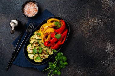 Izgara sebze parçaları kabak, kırmızı ve sarı biber tabakta kişniş buketi, mangal kömürünün üzerinde salata. Üst Manzara. Barbekü konsepti