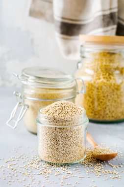 Kavanozda çiğ quinoa taneleri. Gri mutfak masasında sağlıklı vejetaryen yemek. Seçici odaklama.