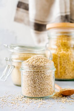 Kavanozda çiğ quinoa taneleri. Gri mutfak masasında sağlıklı vejetaryen yemek. Seçici odaklama.