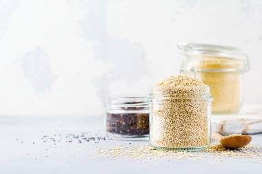 Kavanozda çiğ quinoa taneleri. Gri mutfak masasında sağlıklı vejetaryen yemek. Seçici odaklama.