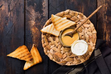 Koyu eski ahşap masa üzerinde açık renkte yoğuşmalı veya buharlaştırılmış süt. Rustik tarz. Üstte görüntü.