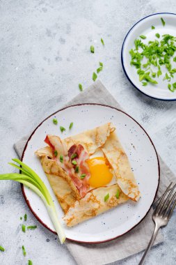 Sahanda yumurta, peynir, pastırma ve yeşil soğan bir ışık gri beton zemin üzerine kahvaltıda krep.