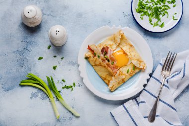 Sahanda yumurta, peynir, pastırma ve yeşil soğan bir ışık gri beton zemin üzerine kahvaltıda krep.