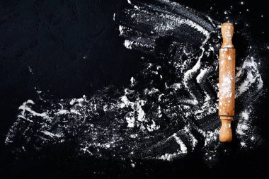 Koyu siyah pişirme arka plan üzerinde un ile Oklava pin, üst görünüm, metin için kopya alanı, menü, tarifi. Düz yatıyordu.