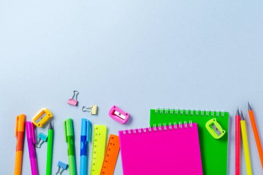 Defter, renkli kalemler, cetvel, kalem, silgi, keskinleştirme ve daha fazlası. Mavi arka planda okul ve ofis kırtasiye. Kavram okula geri döndü. Üstte görüntü.