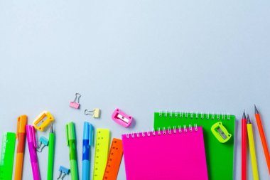 Defter, renkli kalemler, cetvel, kalem, silgi, keskinleştirme ve daha fazlası. Mavi arka planda okul ve ofis kırtasiye. Kavram okula geri döndü. Üstte görüntü.
