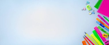 Defter, renkli kalemler, cetvel, kalem, silgi, keskinleştirme ve daha fazlası. Mavi arka planda okul ve ofis kırtasiye. Banner Kavramı okula geri döndü. Üstte görüntü.