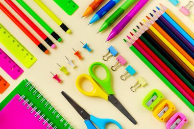 Defter, renkli kalemler, cetvel, kalem, silgi, keskinleştirme ve daha fazlası. Sarı arka planda okul ve ofis kırtasiye. Kavram okula geri döndü. Üstte görüntü.