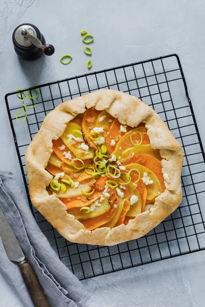 Pumpkin, potato, feta cheese and leek galette pie plate on gray concrete table background. Top view.l