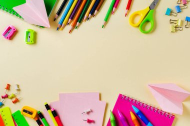 Defter, renkli kalemler, cetvel, kalem, silgi, keskinleştirme ve daha fazlası. Sarı arka planda okul ve ofis kırtasiye. Kavram okula geri döndü. Üstte görüntü.