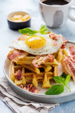 Hafif eski beton arka plan üzerinde kahvaltı için kızarmış pastırma, yumurta ve baharat ve fesleğen ile parmesan peyniri ile Peynir Waffle. Üstte görüntü.