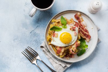 Hafif eski beton arka plan üzerinde kahvaltı için kızarmış pastırma, yumurta ve baharat ve fesleğen ile parmesan peyniri ile Peynir Waffle. Üstte görüntü.